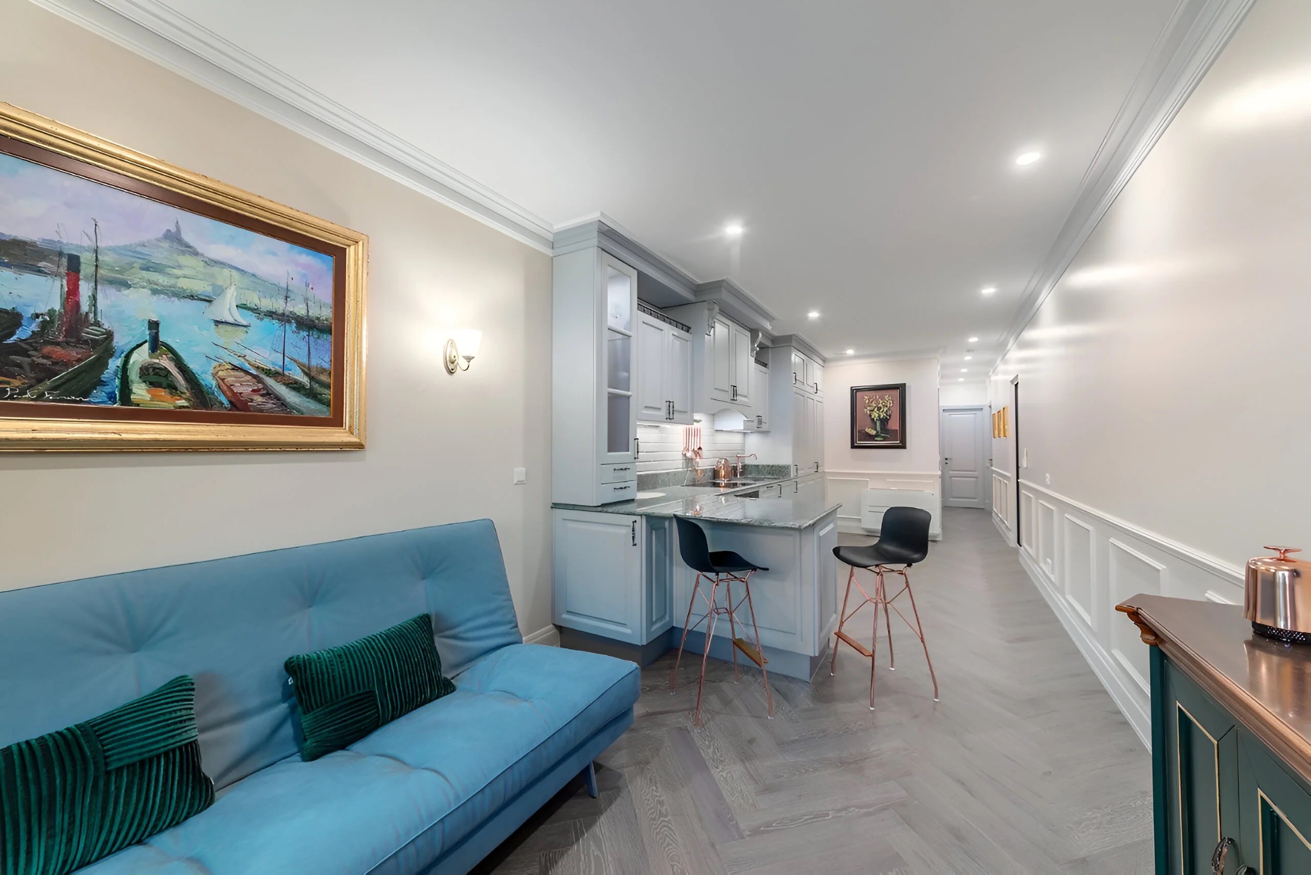 Vue d'ensemble de la pièce de vie montrant les moulures murales blanches et l'harmonie des tons bleus et gris dans un appartement de luxe.