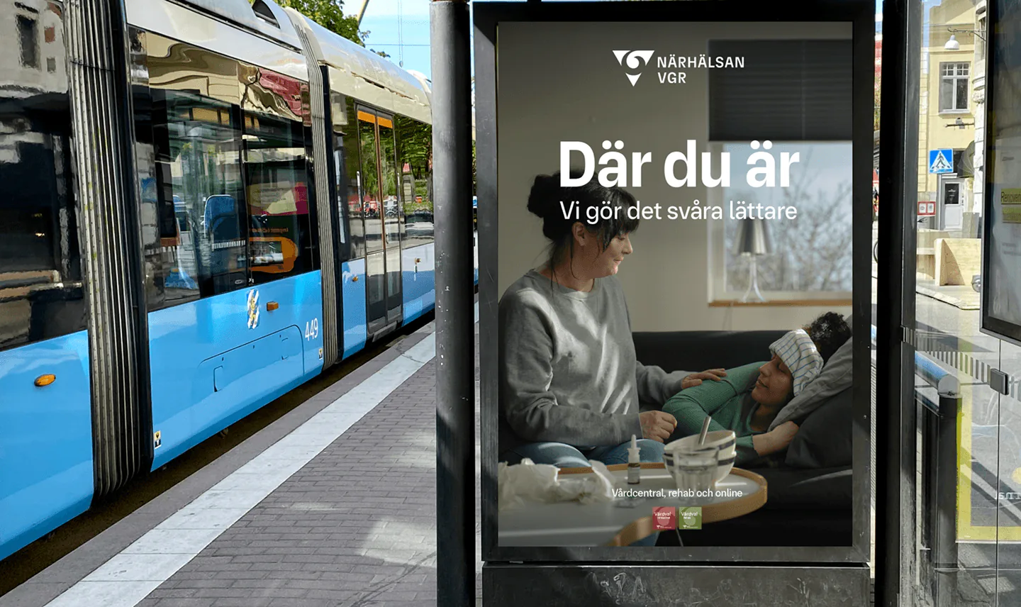Reklampelare vid en spårvagnshållplats med Närhälsans affisch Där du är, Vi gör det svåra lättare