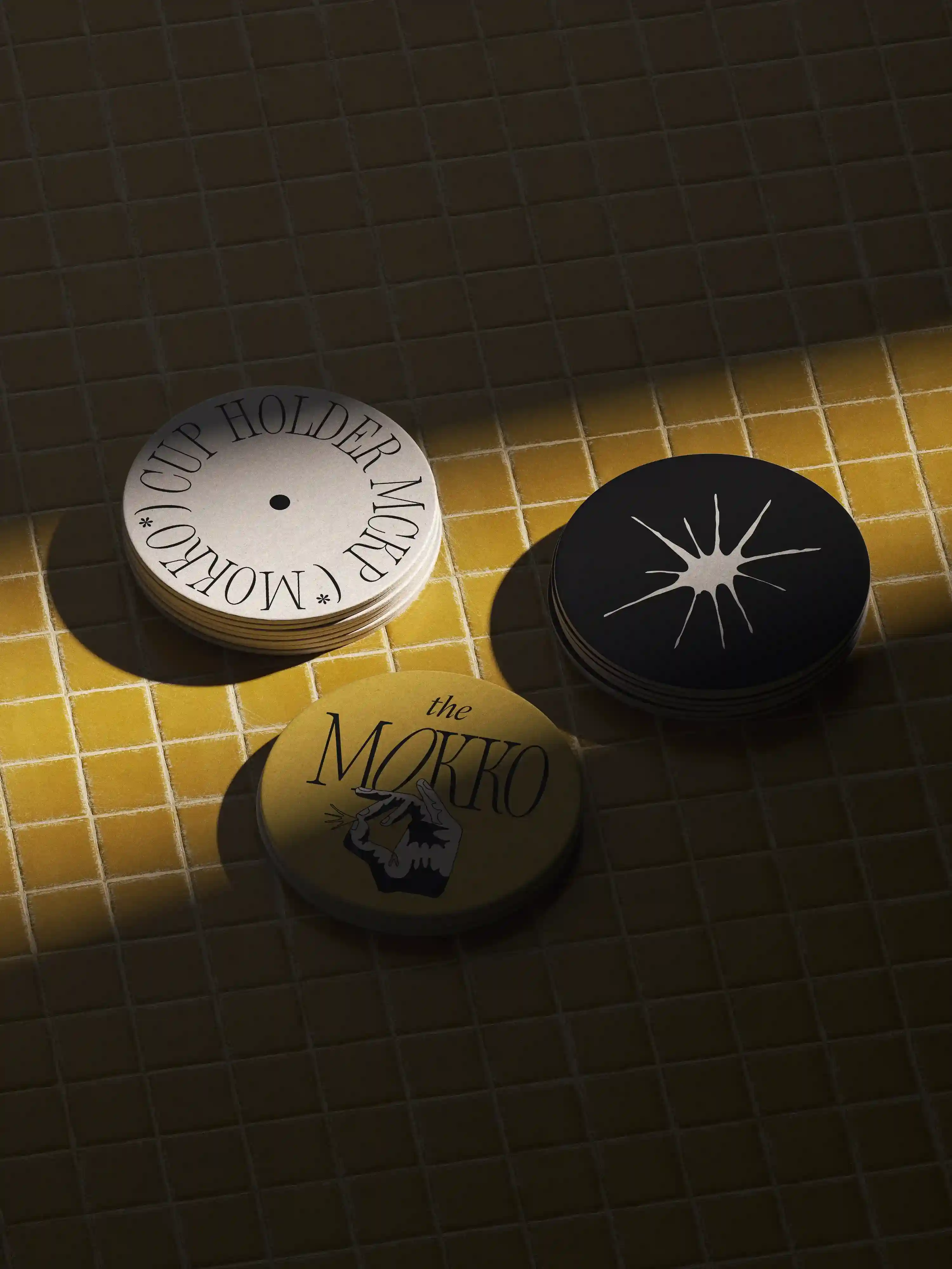 Stack of circular branded coasters on yellow tiled table