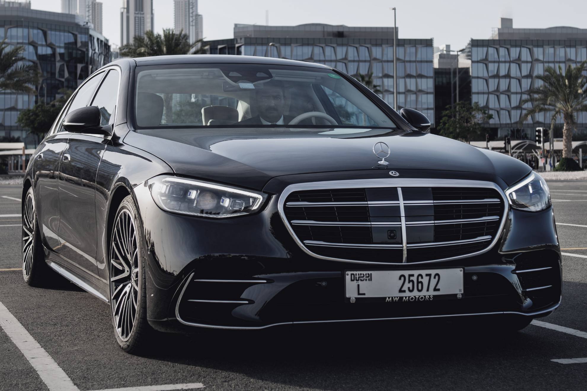 black mercedes benz s class parked with skyscrapers in the background