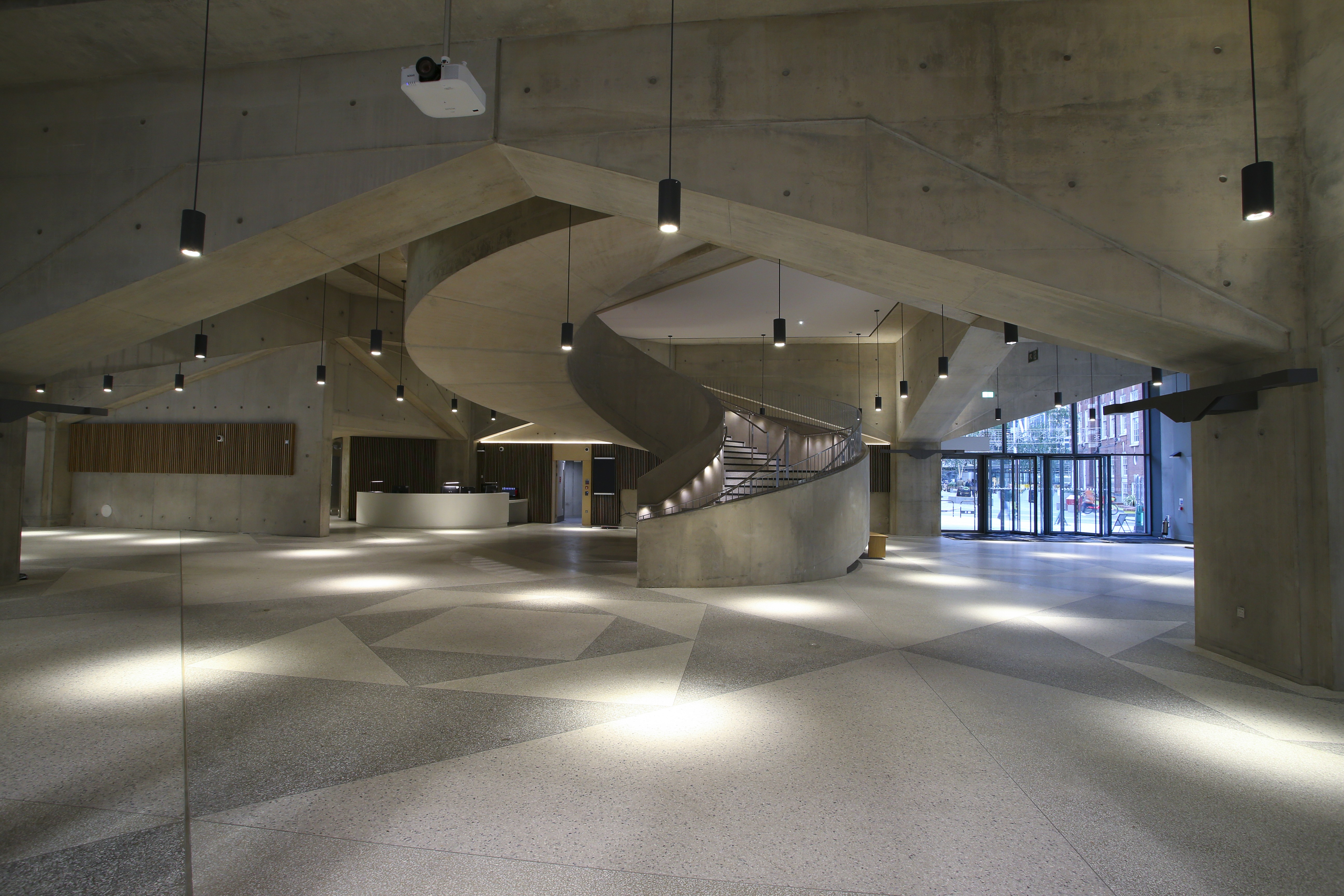 Modern building with a sleek glass facade and illuminated orange lighting, reflecting on a polished surface, creating a futuristic and elegant atmosphere