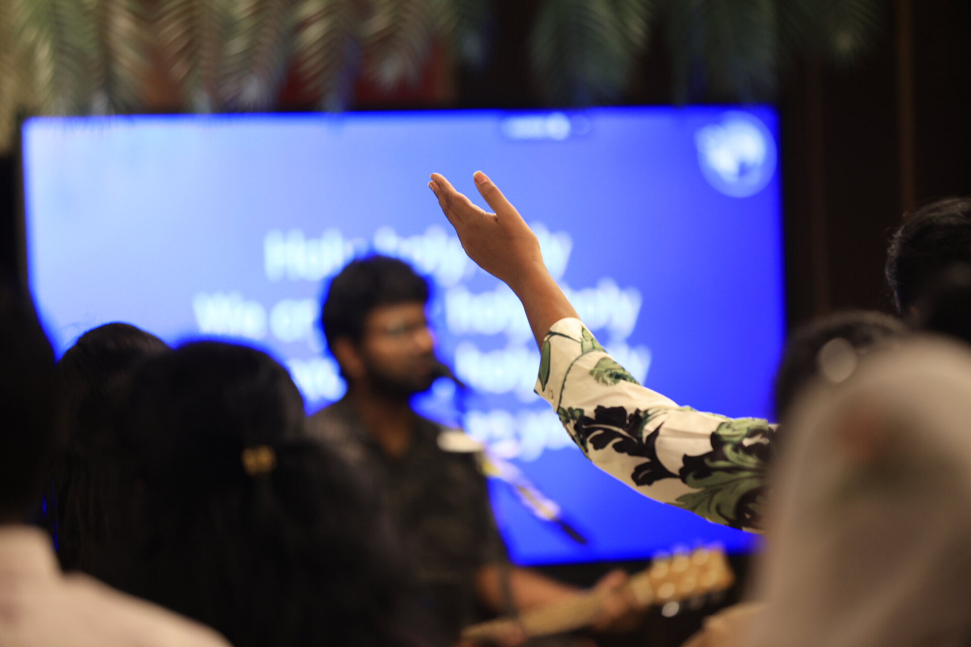 A raised arm in worship in front of a lyric screen