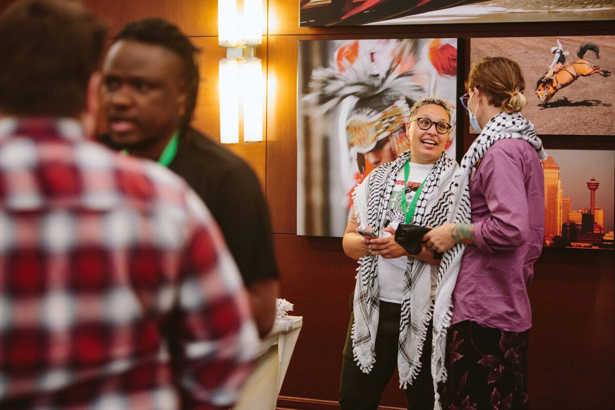 A group of people interacting in a lively setting, with a colorful backdrop and posters in the background.