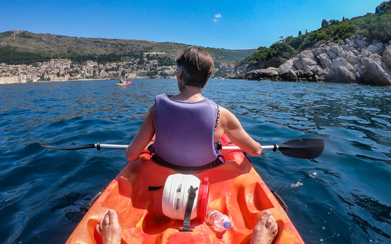 Kayaker paddling near Old Town Walls with coastal view.