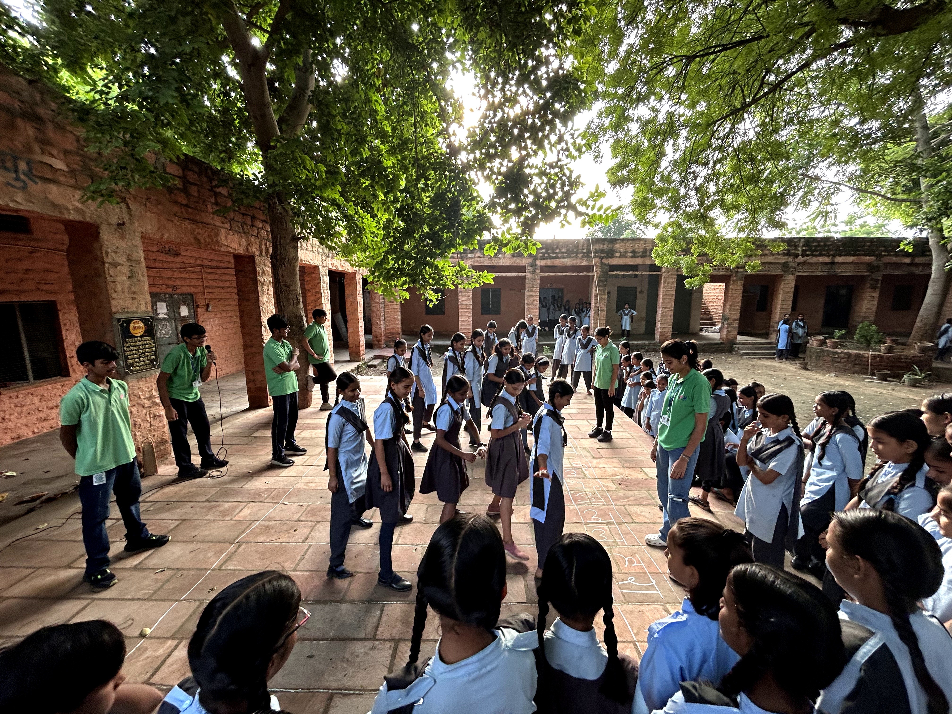 A student wearing a red uniform sits while holding a book in his hands