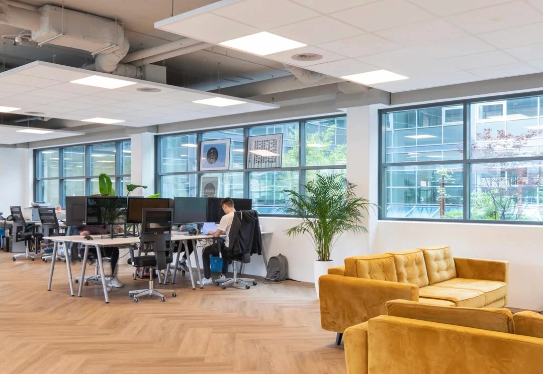 Kantoorlounge met blauwe bank, leren fauteuils en open kast