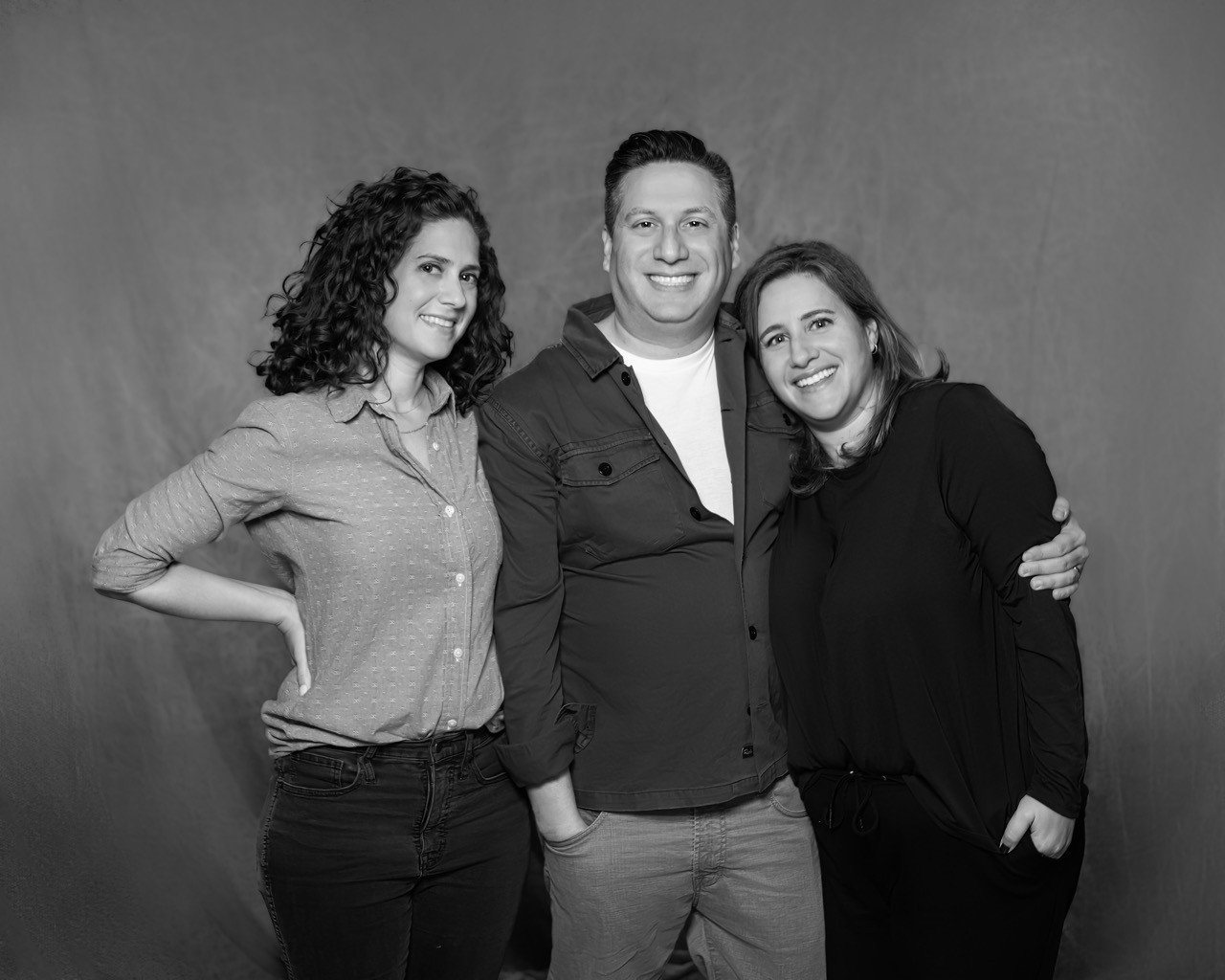 Black-and-white photo of the Korman siblings standing closely together.