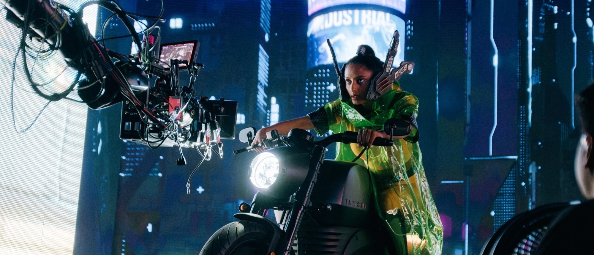 A crane camera filming a performer on a motorcycle on a neon virtual production set