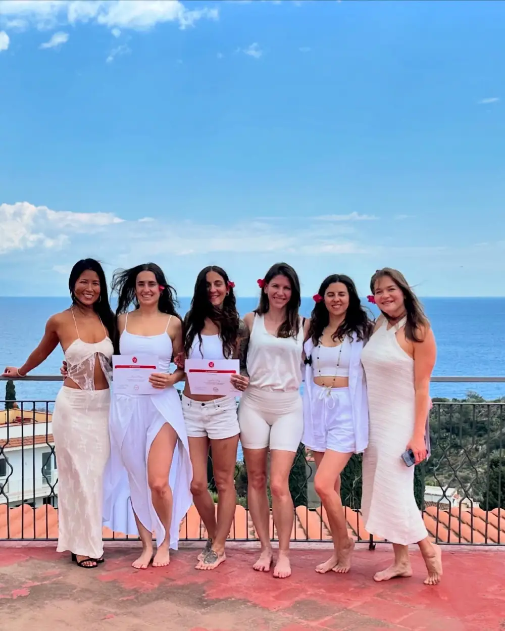 Yoga students practicing Warrior II pose on the beach during a beautiful Bali sunset.