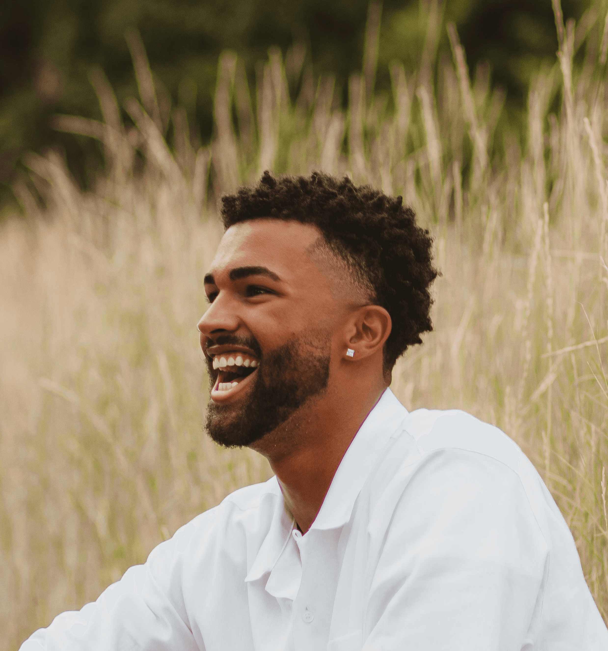 man in white polo shirt sitting on brown rock
