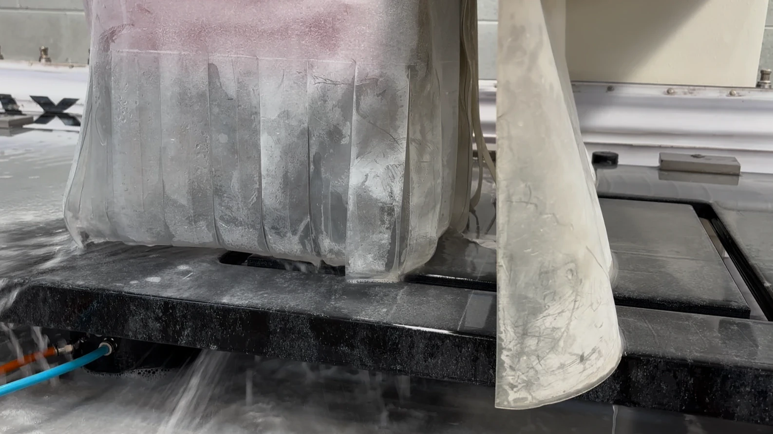 CNC router with water curtain shaping the edge of a stone benchtop