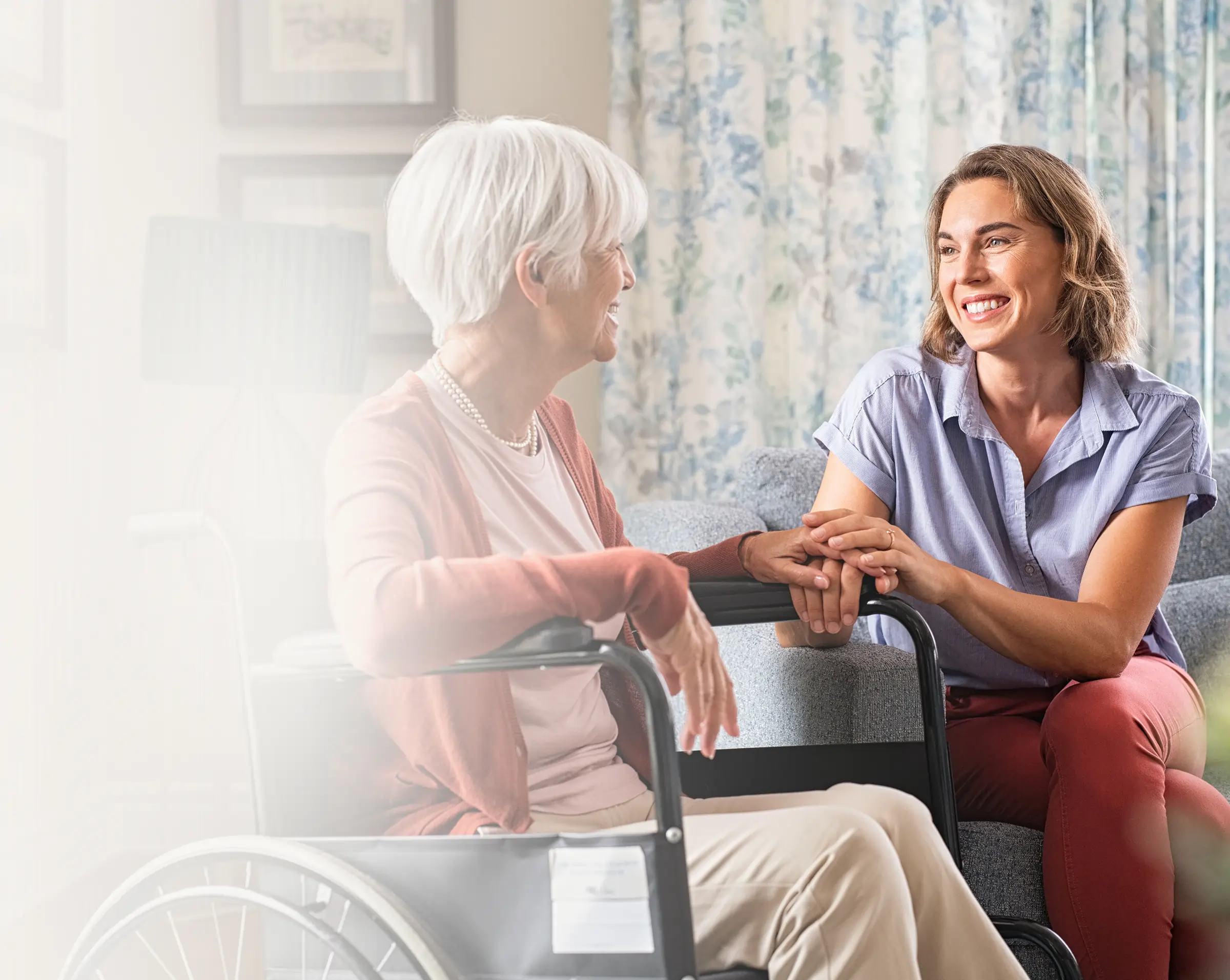 Senior woman in a wheelchair sharing a laugh with her caregiver during an at-home visit in the Twin Cities