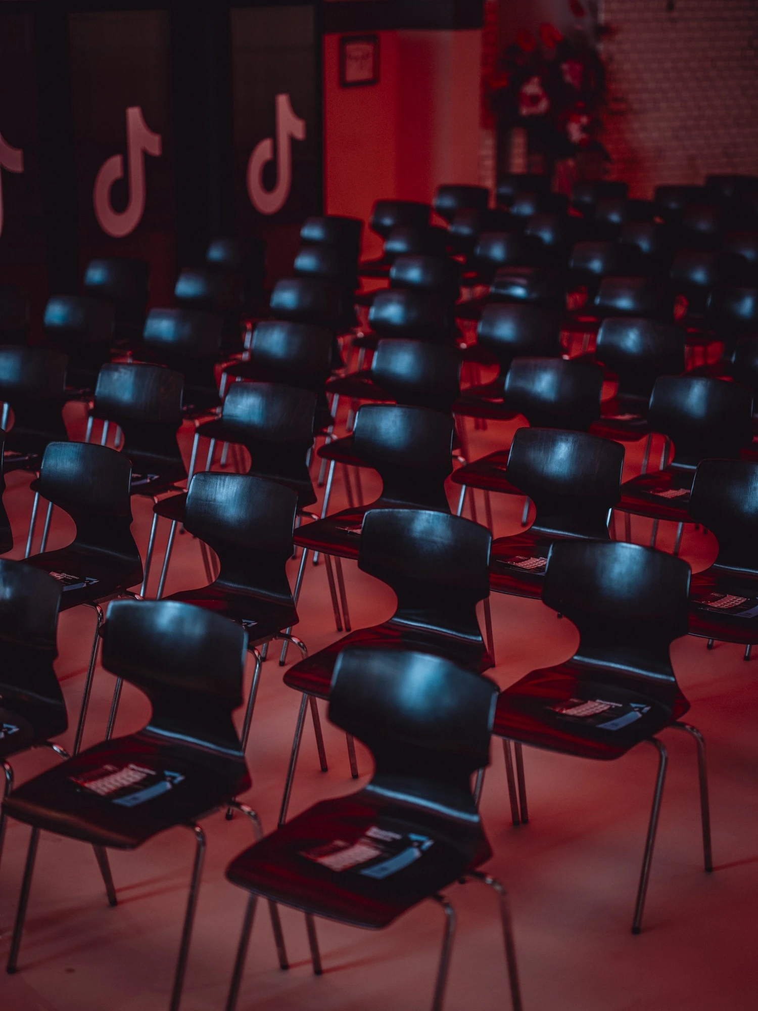 Rows of black chairs with goodie boxes in red light under TikTok logos on the wall.
