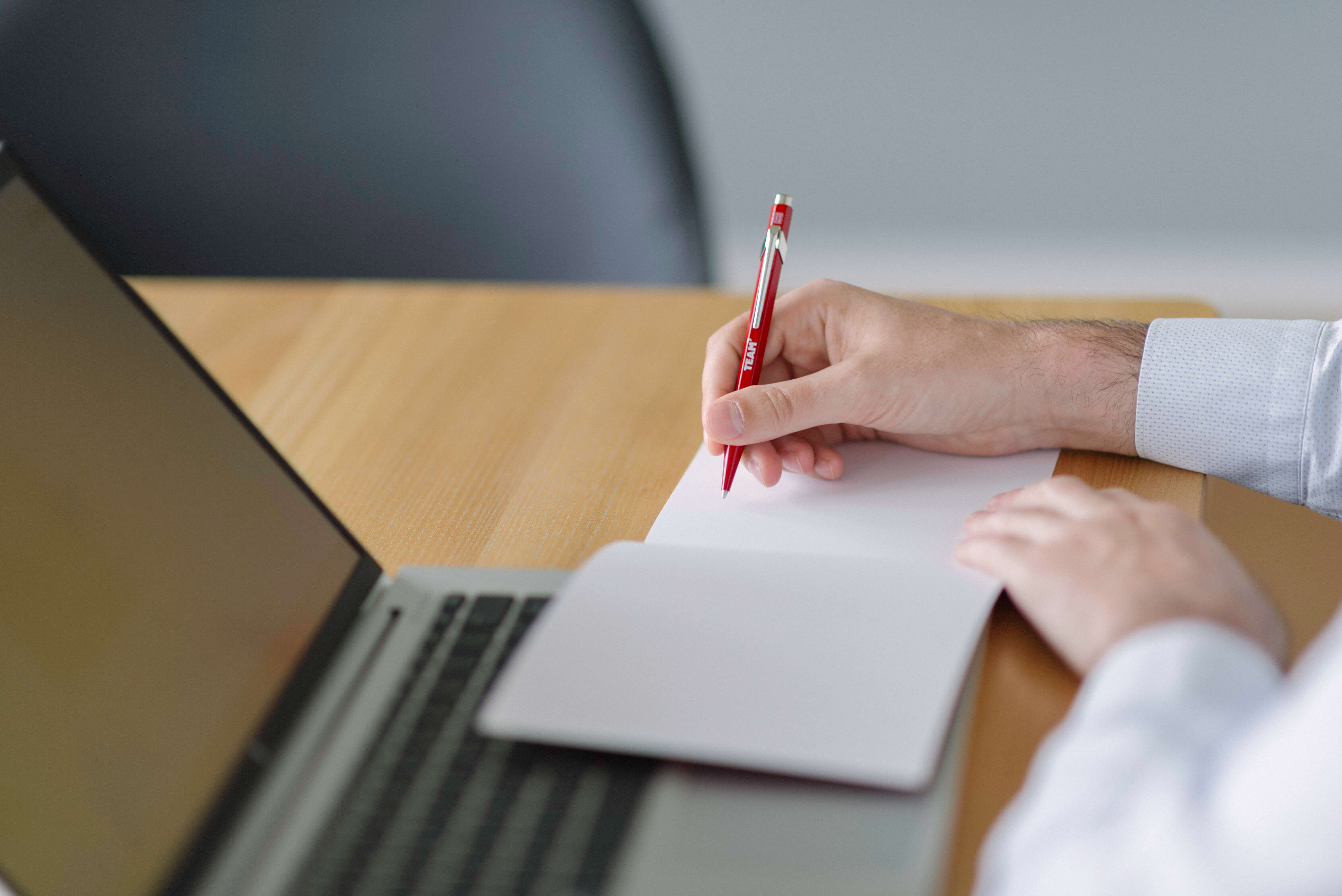 Close-up of a Team-branded pen and notepad beside a laptop, showcasing Team’s merchandise.