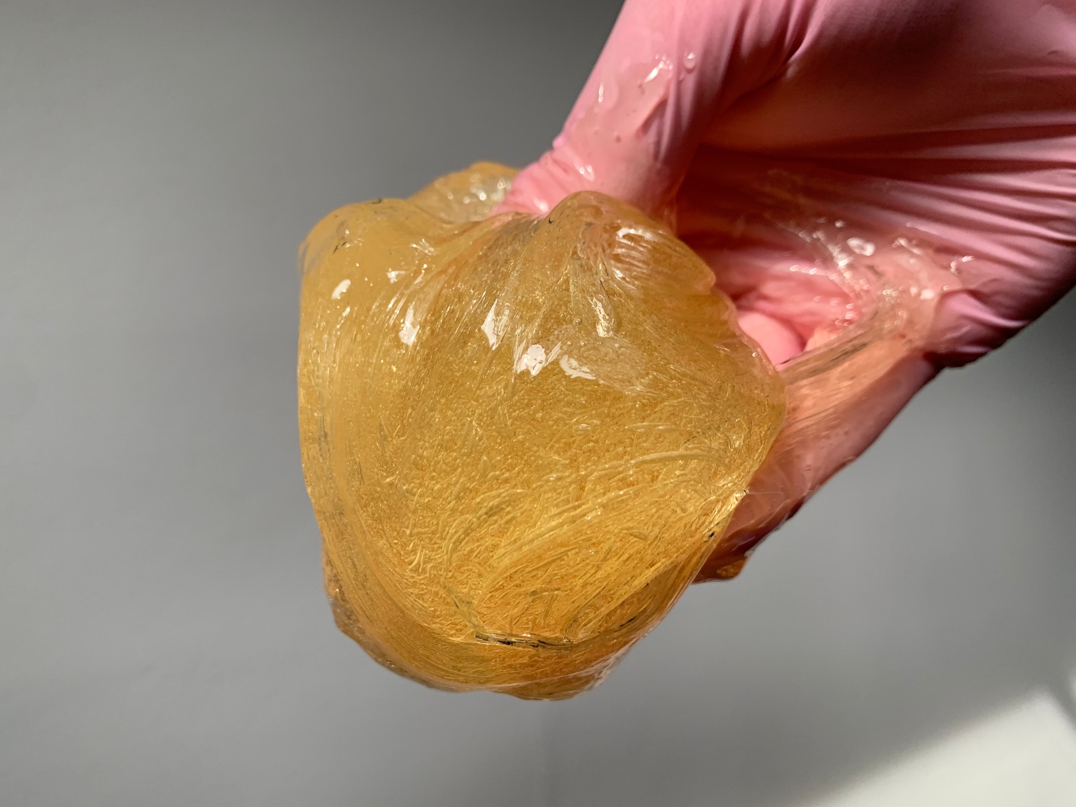 Ball of sugar paste held in gloved hands during a sugaring treatment