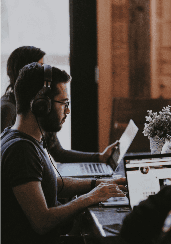 An IT expert sitting on a table and working on a laptop.