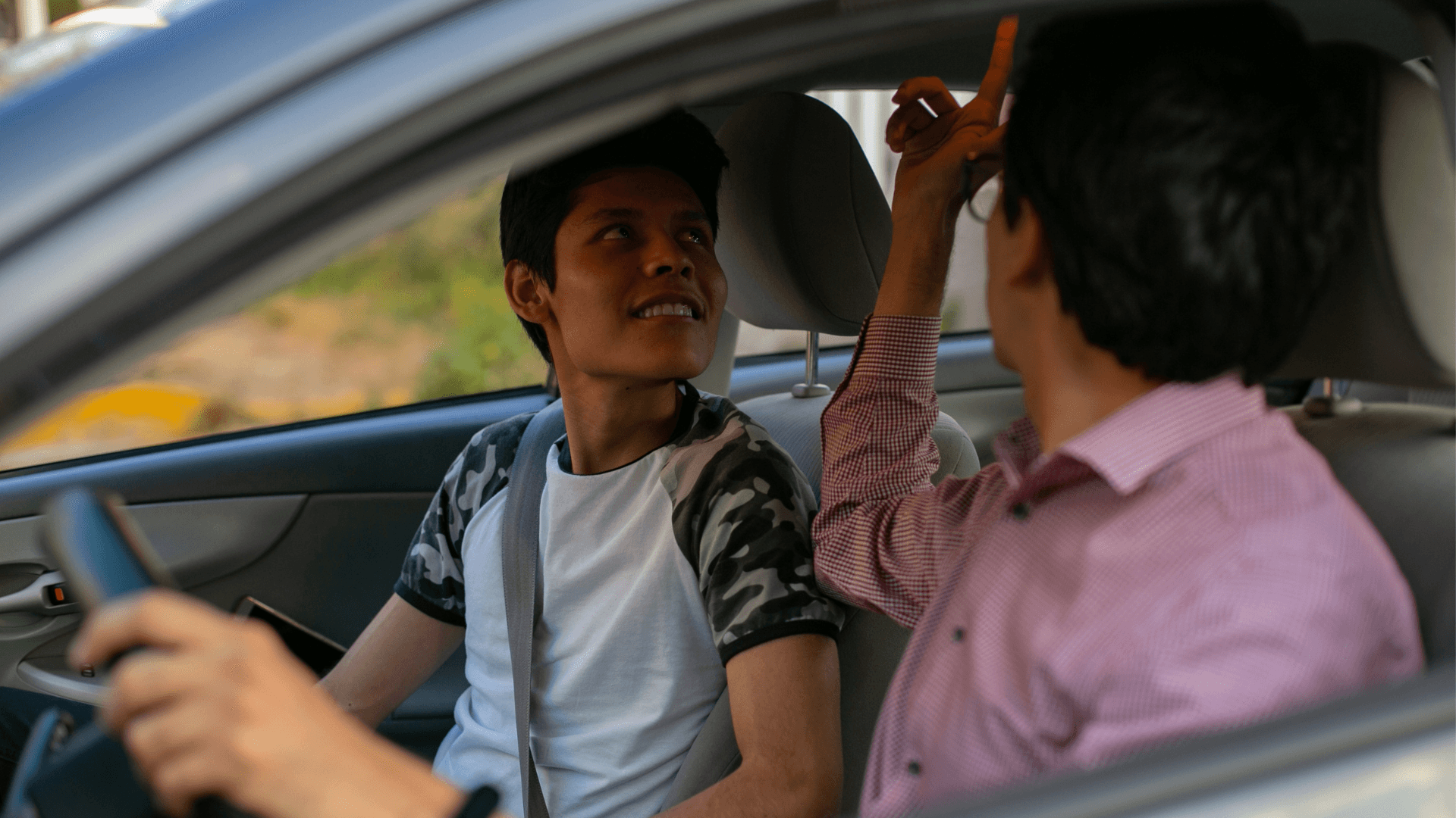 Adolescent in the passenger seat of a vehicle, and an adult in the driver seat. 
