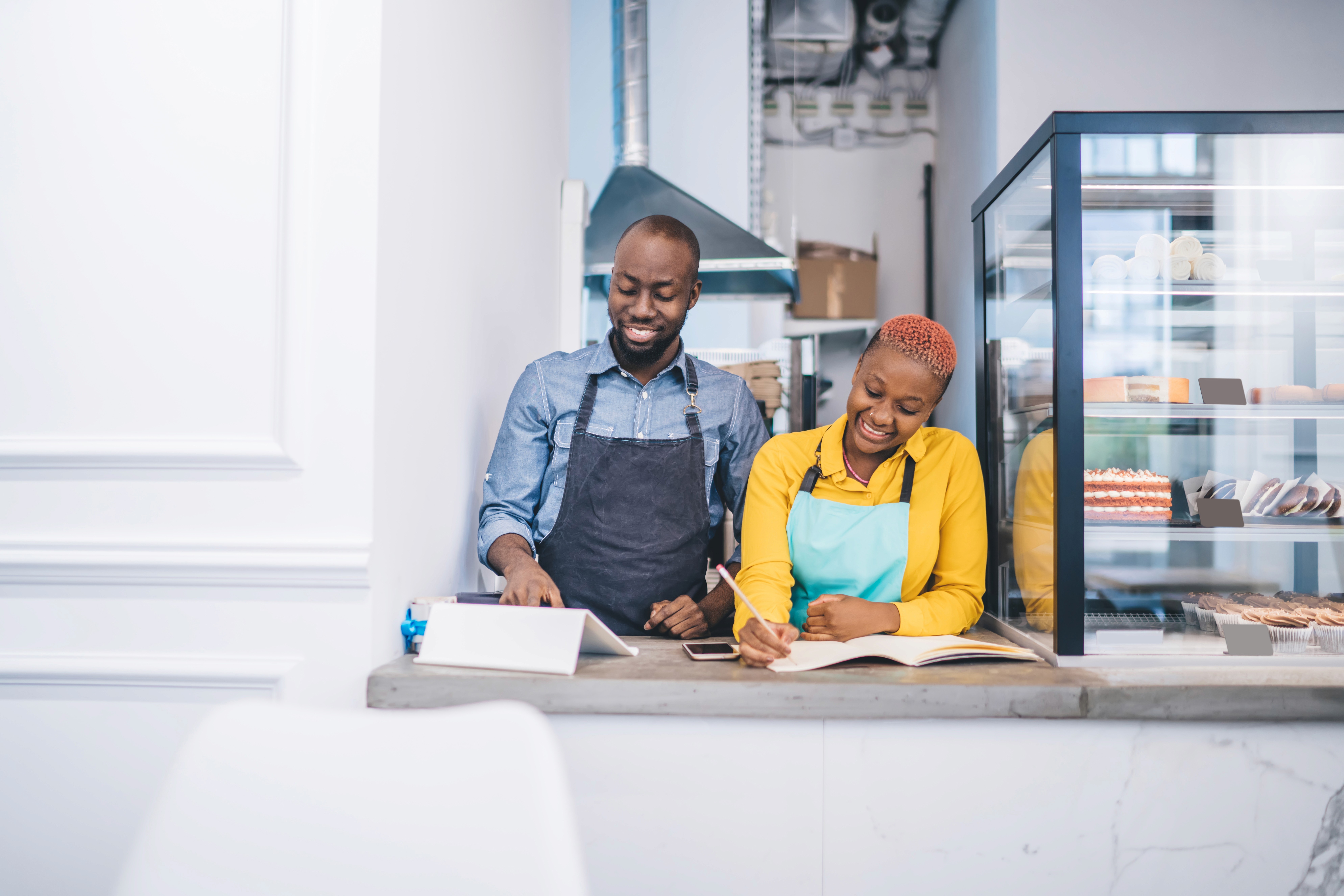 A bakery owner and staff member working together at the counter in a bright, modern shop.