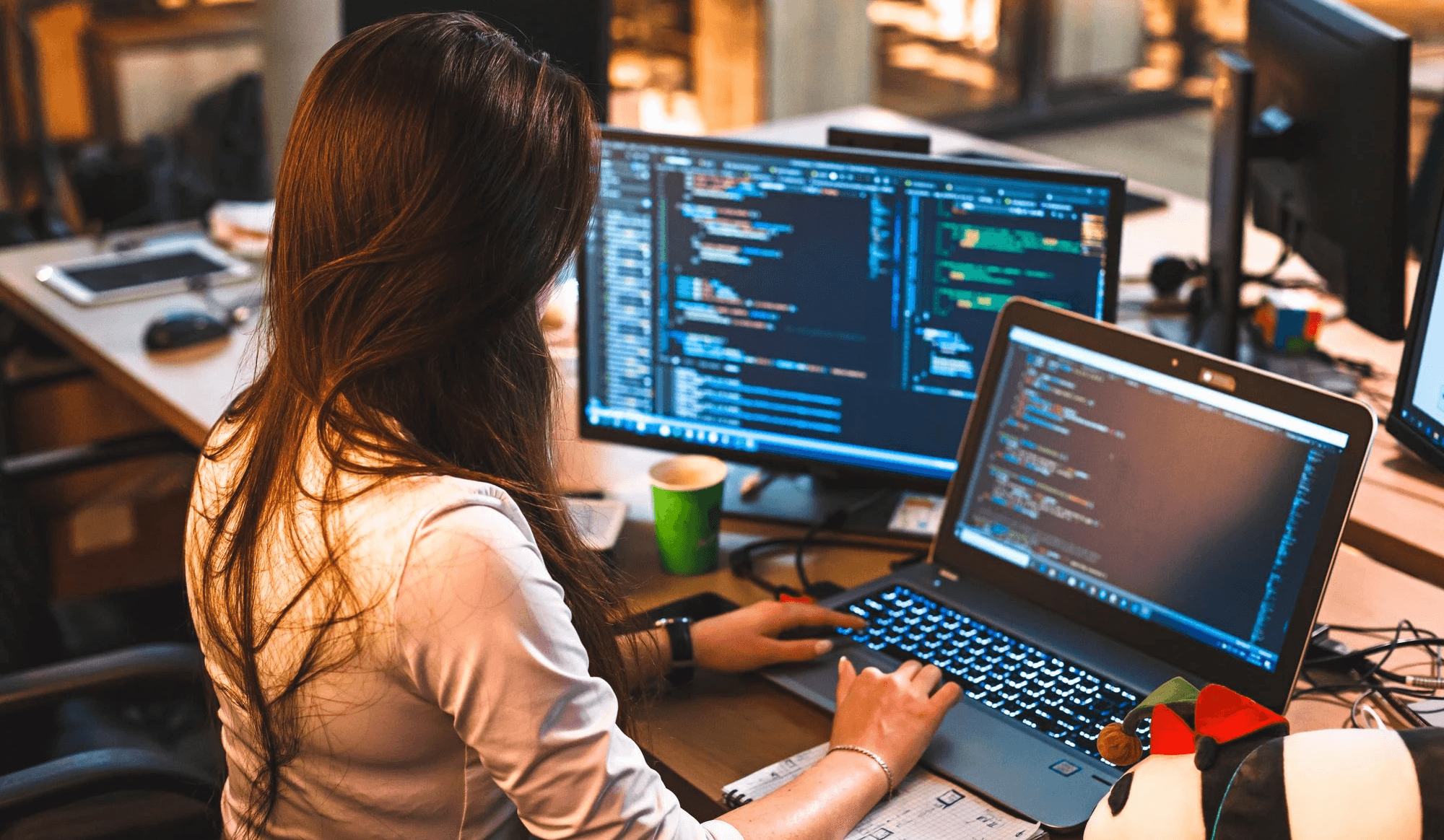 Woman coding on laptop and monitor - How to Hire a Front-End Developer