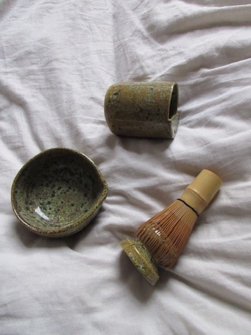 Small olive-toned ceramic cup with bamboo whisk.
