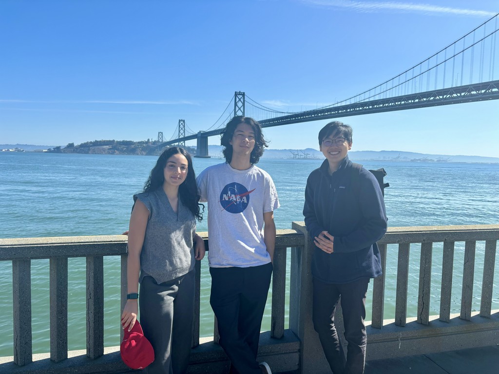 two uncovr ai employees pointing at a whiteboard and smiling at the camera.