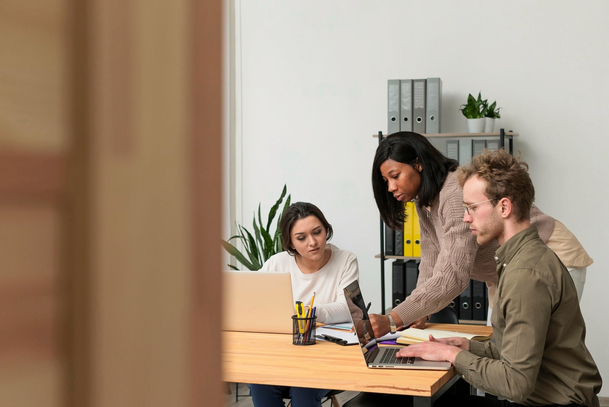 duas mulheres e um homem sentados na mesa de um escritório fazendo planos no computador e definindo objetivos e metas