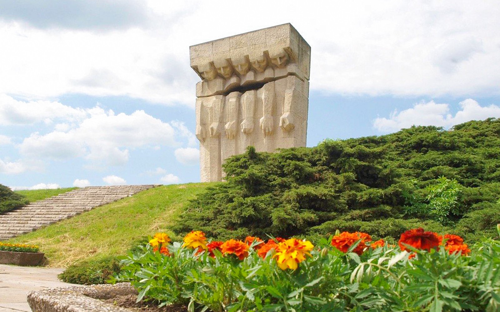 Monumentet til ofrene for fascismen Plaszow i Krakow med omgivelser av grøntområder og blomster.