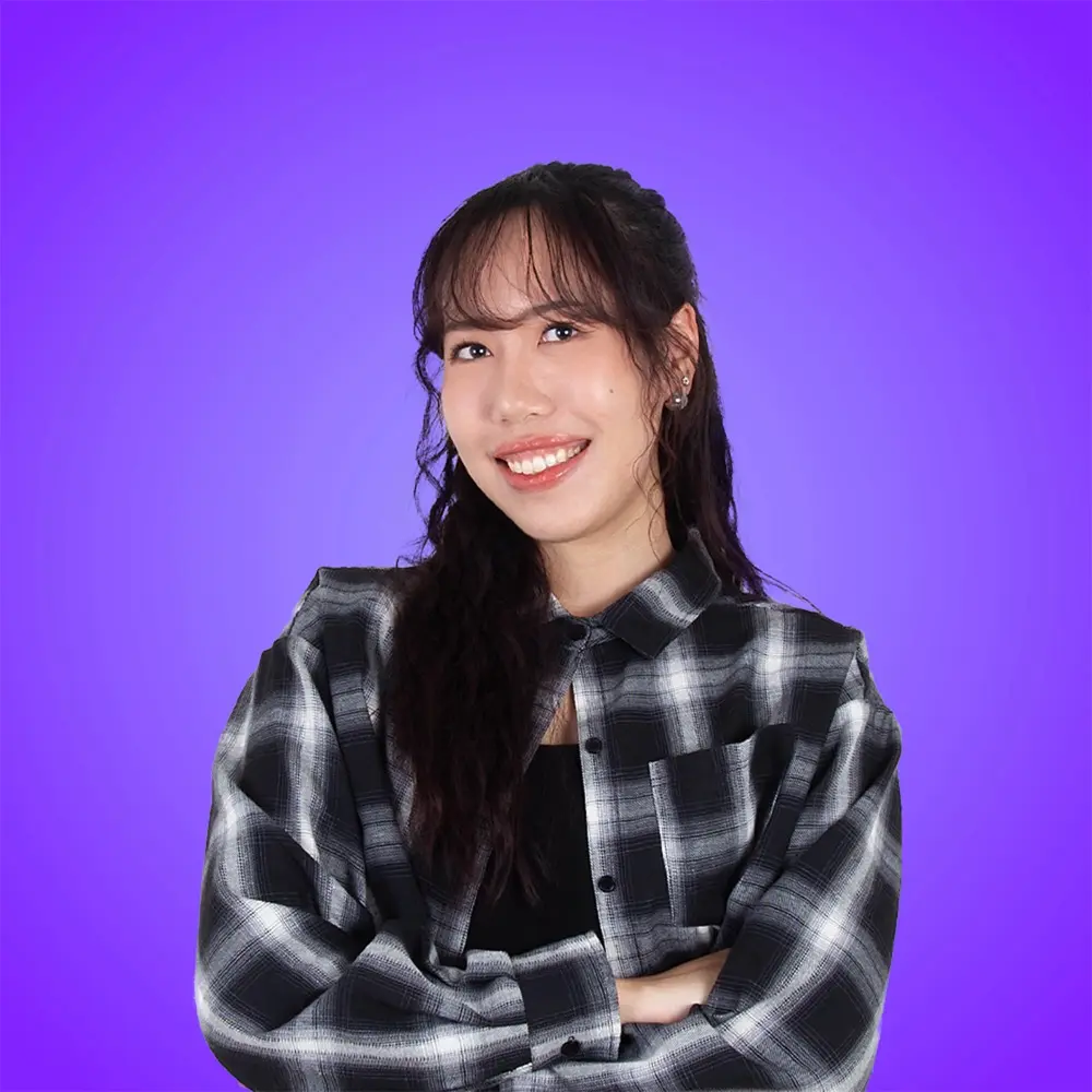 A smiling person in a black suit stands against a light blue background.