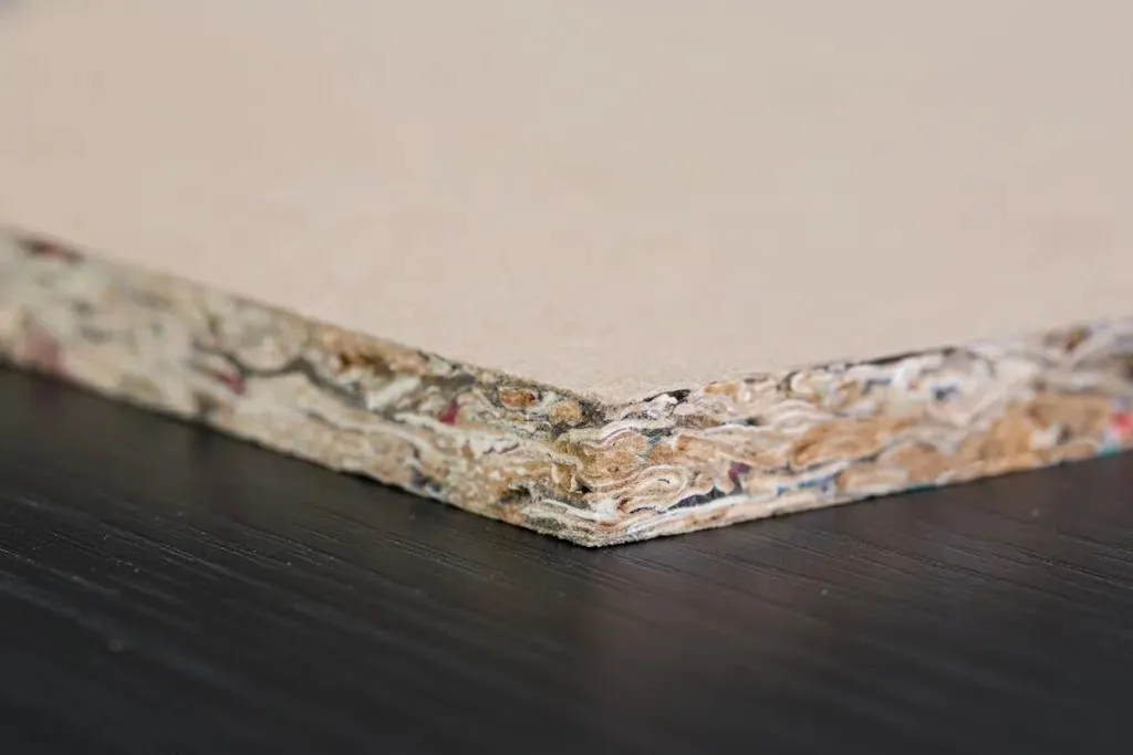 Detail řezu protihlukové desky se zobrazením vrstev materiálu – béžový povrch a černá izolační vrstva