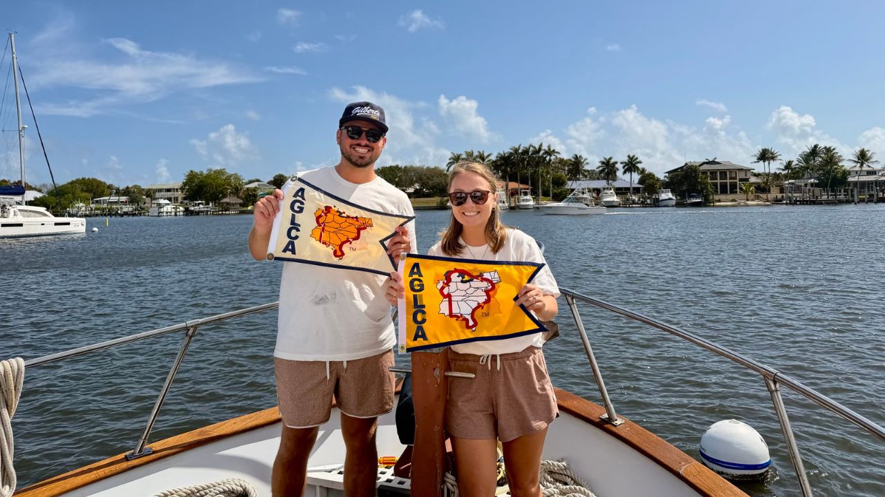 Navigating Nietzel standing on their boat holding the Gold Loopers flag after completing America’s Great Loop