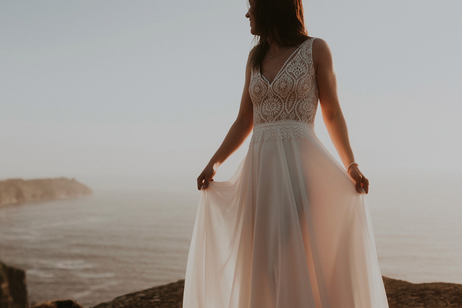 bride in wedding dress at cliffs of moher ireland at sunset