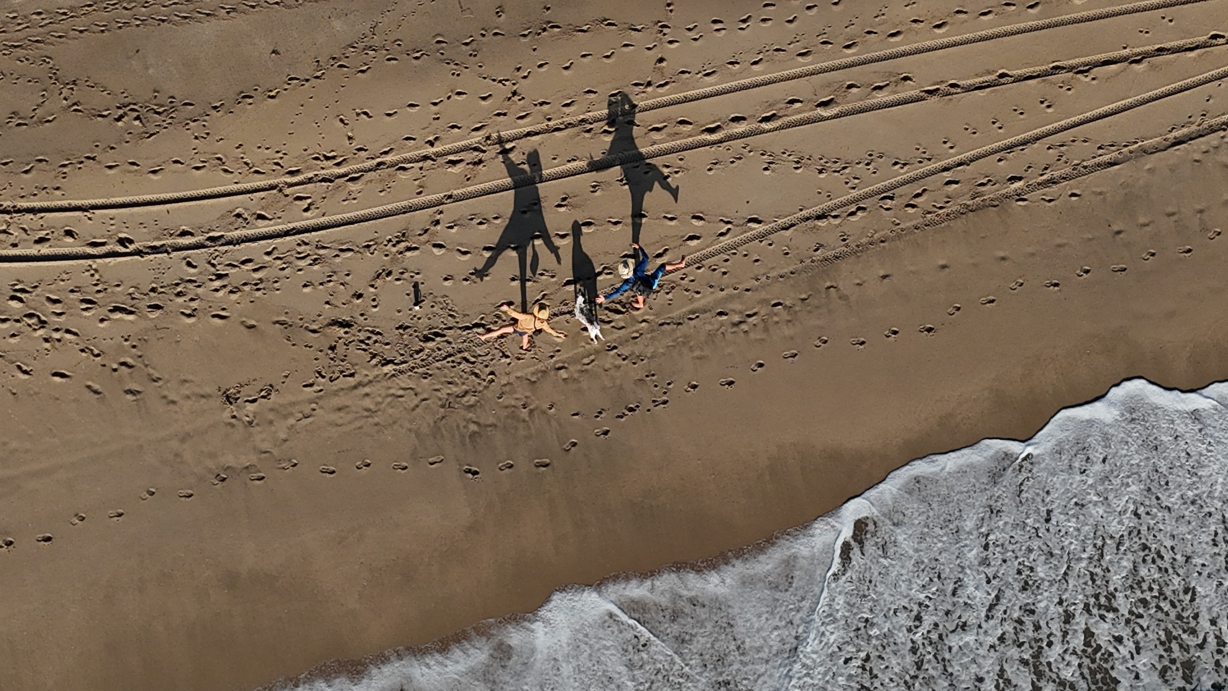 Two people dancing with their shadows on the beach