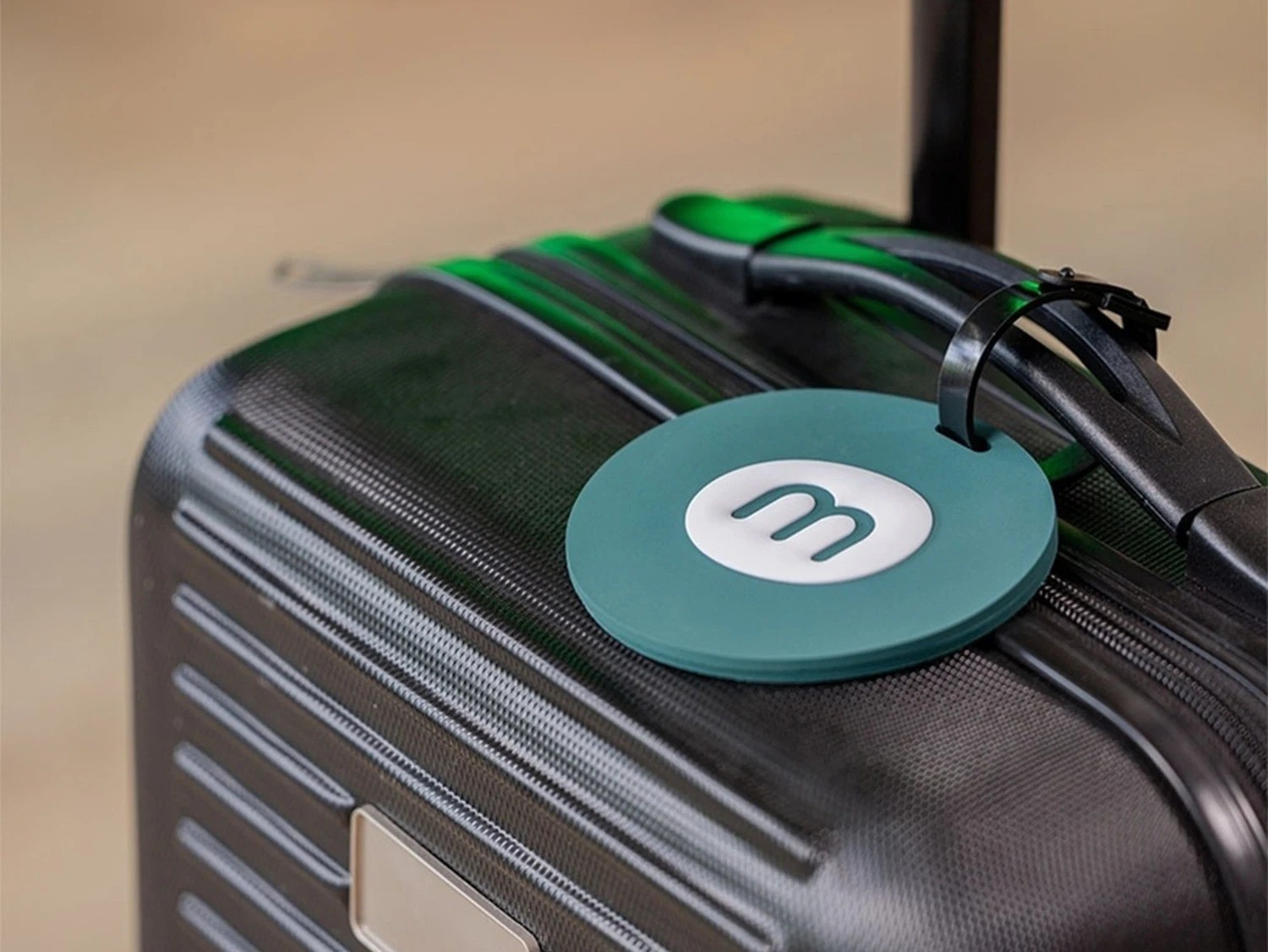 Close-up van een koffer met een teal bagagelabel met een monday merch logo