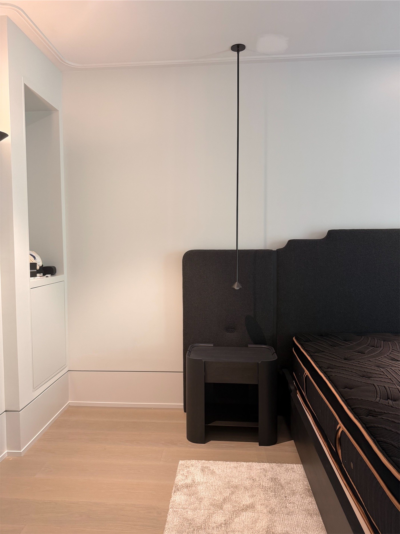 A bedroom with an upholstered bed under a single pendant