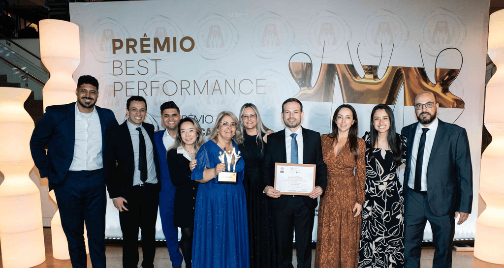 Executivos da BELLINATI PEREZ posando com troféu ouro e certificado no palco do Prêmio Best Performance 2025