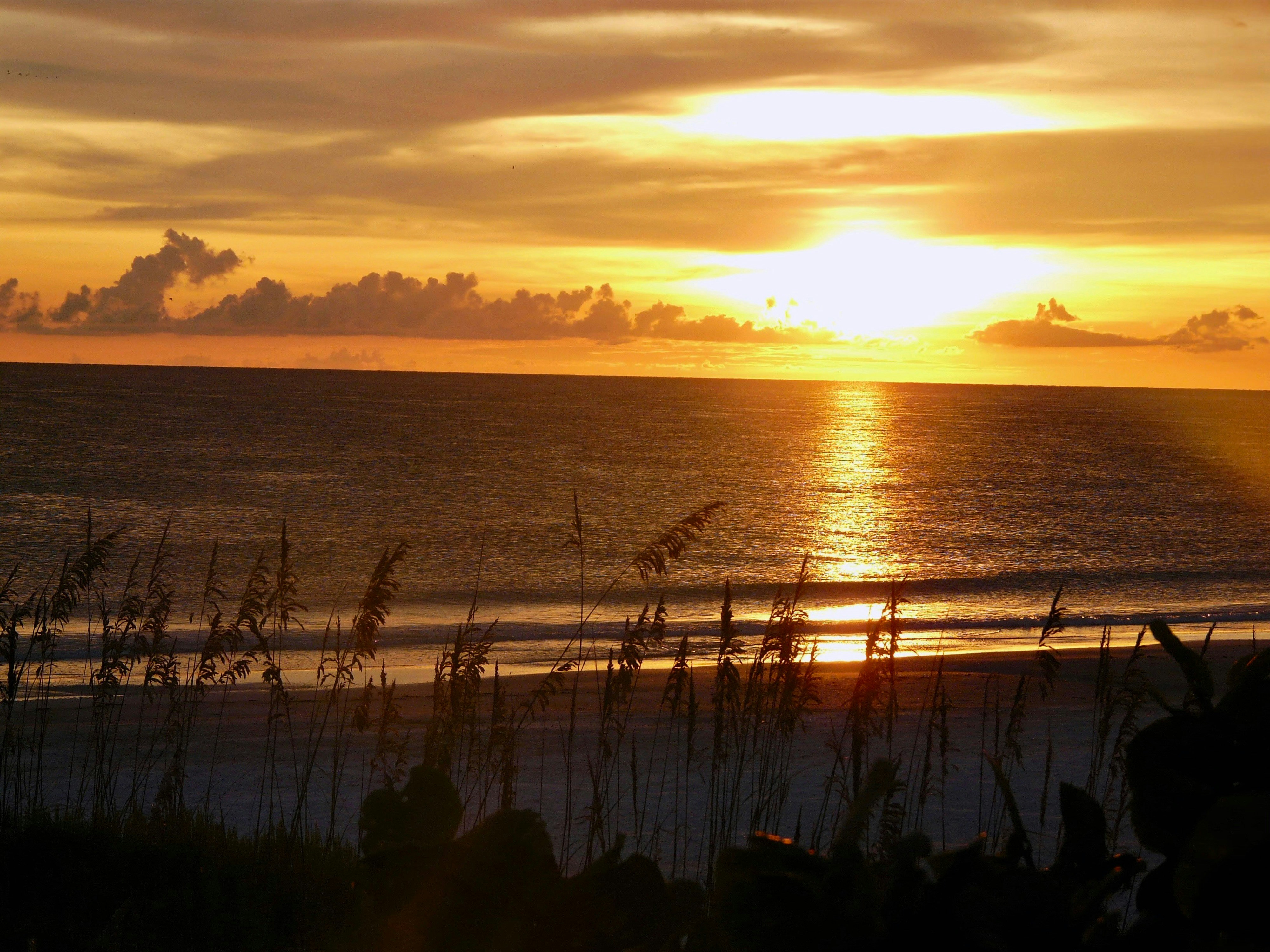 the sun is setting over the ocean on the beach att anna maria island