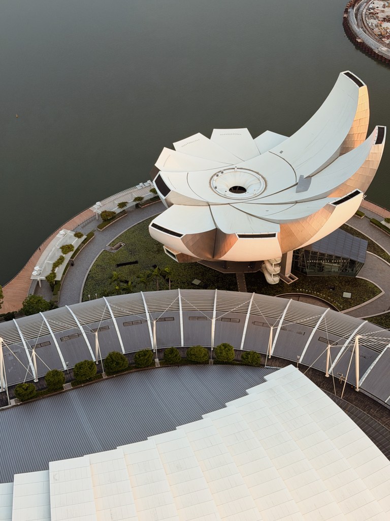 Aerial view of the Marina Bay Sands ArtScience Museum in Singapore, featuring its distinctive flower-like architecture and surrounding green spaces.