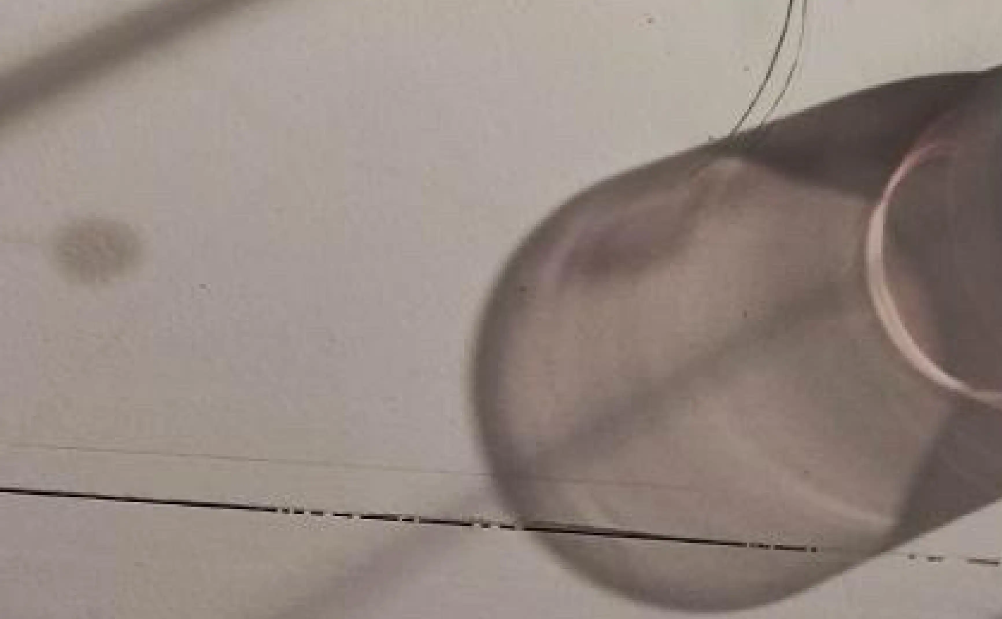 Sombra difusa de copa de vidrio sobre superficie clara para fotografía conceptual de luz y textura.