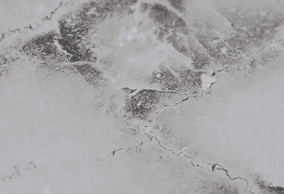 Close-up of a marble surface with visible cracks and natural patterns, highlighting imperfections in the stone.