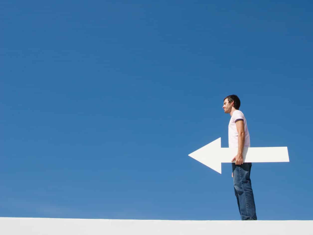 Hombre sosteniendo flecha blanca hacia la izquierda contra un cielo azul. para Antena3