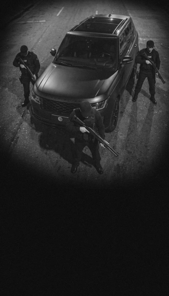 Seguranças armados fazendo a segurança de um automóvel.