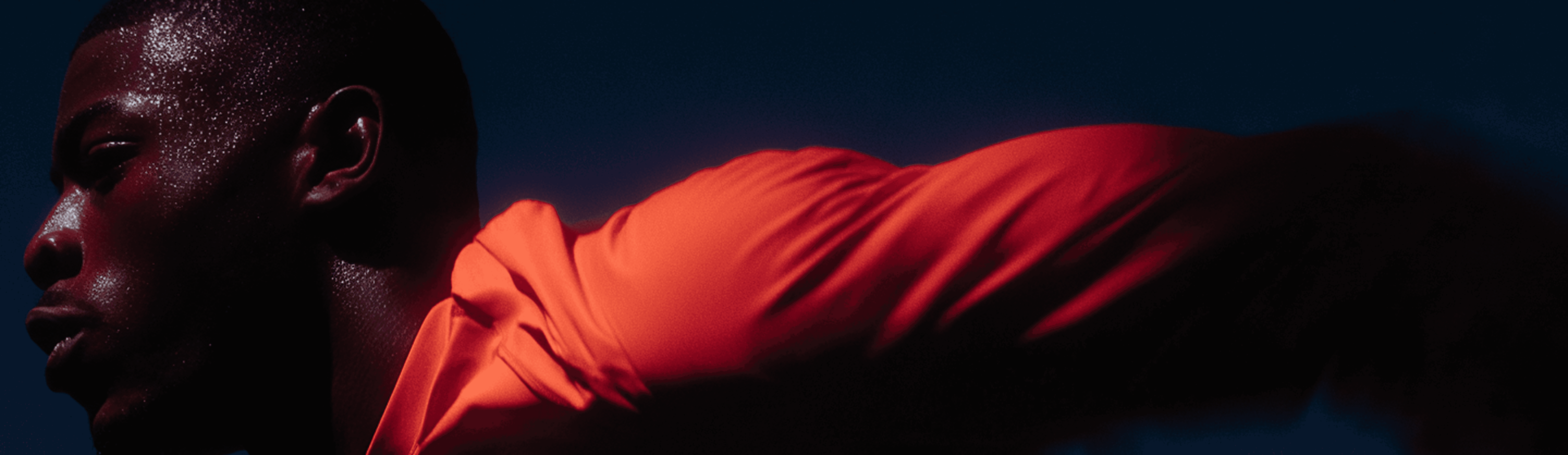 A motion blurred action shot of a sweaty runner in orange.