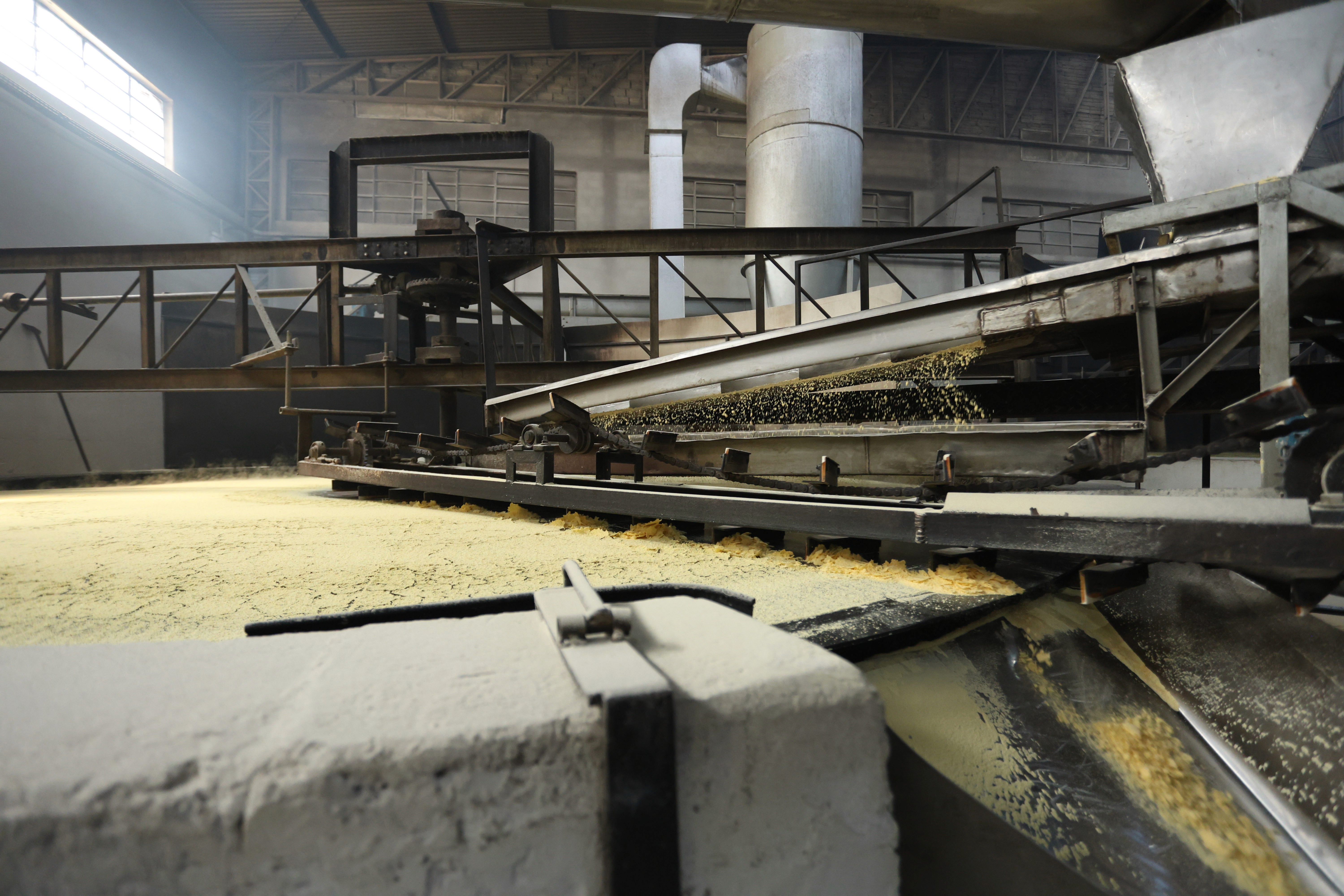 Interior da fábrica da CL Angelo com esteiras transportadoras e silos industriais de produção de farinha de milho