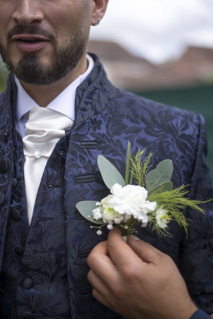 Close-up moment of a groom adjusting his boutonnière — a poetic wedding detail captured in soft natural light. Gros plan sur un marié ajustant sa boutonnière — un détail poétique de mariage saisi dans une lumière naturelle douce.