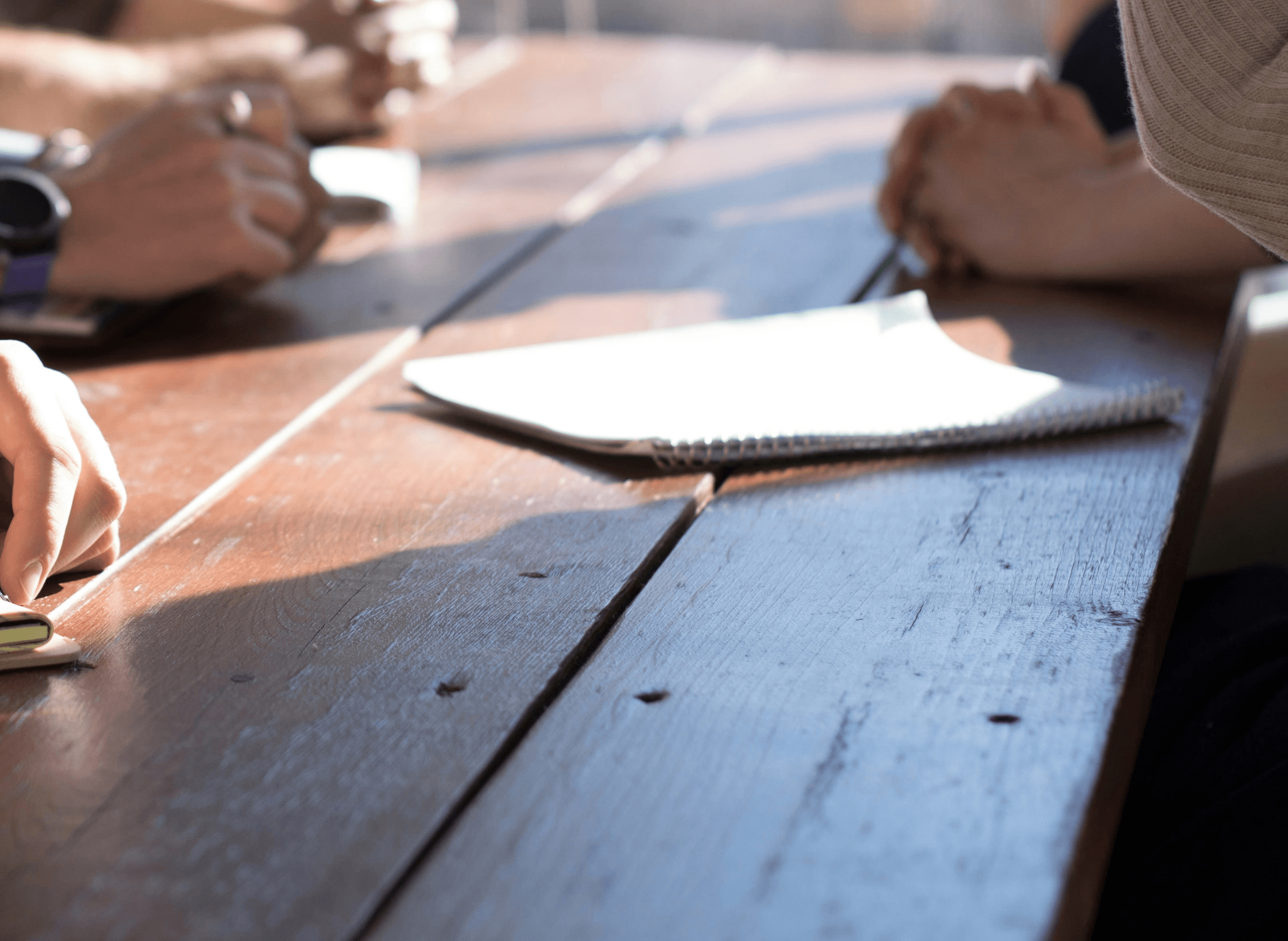 people sitting on chair in front of table while holding pens during daytime
