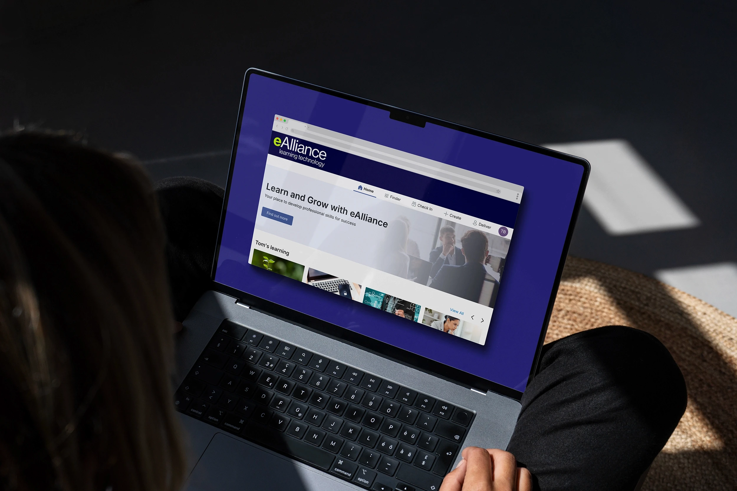 Businness woman sat on rug using apple mac laptop to access ealliance platform
