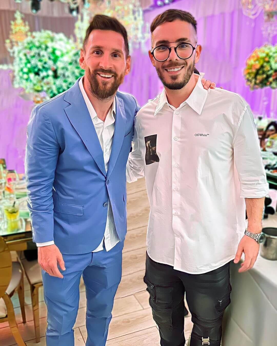 Fer Palacio con Lionel Messi en un evento, Messi con traje celeste y Fer Palacio con camisa blanca.