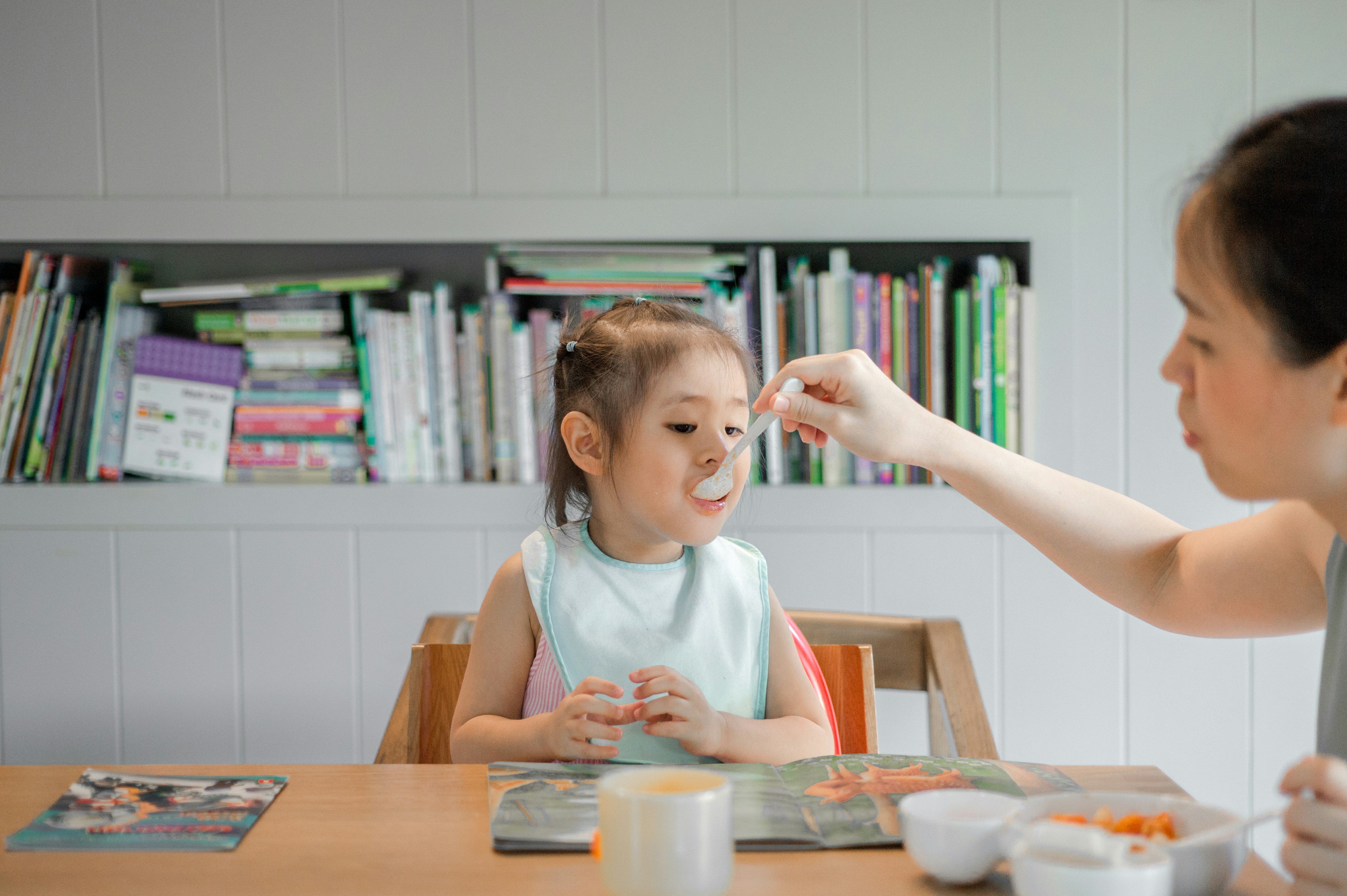  New mum feeding baby with a spoon while managing mealtime one-handed 