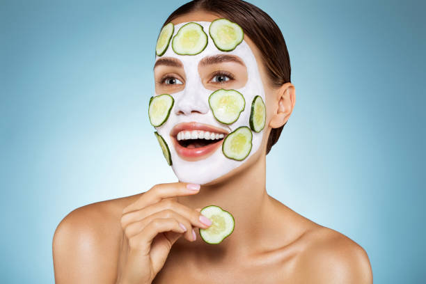 A woman lying down with a towel wrapped around her head, her face glowing with facial oil. She has a peaceful expression, enjoying a skincare treatment.