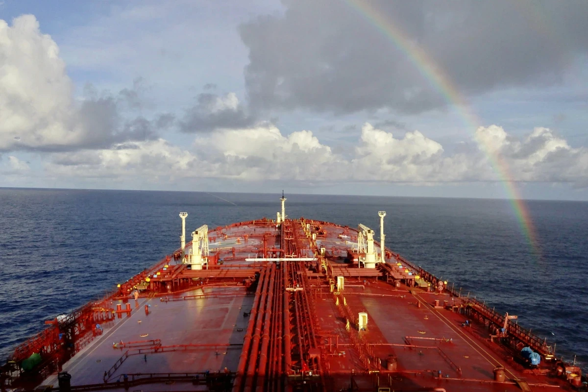 Top deck of red cargo ship with rainbow in sky